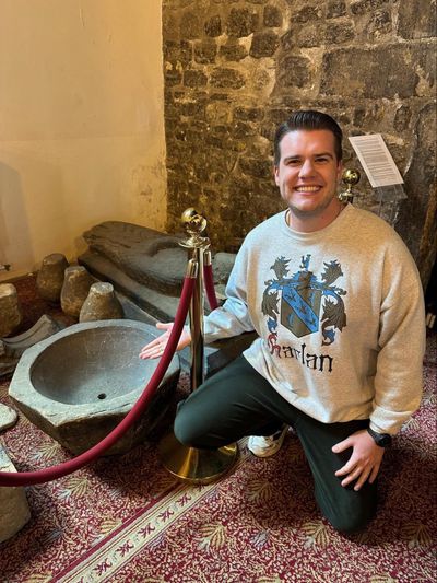 A man smiling next to St. Peter's batismal font